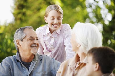 older adults outside with children smiling at one another
