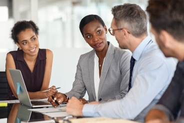 A diverse group of professionals sitting at a conference table having a conversation.