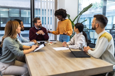 Diverse group of professionals engaging in a discussion around a conference table in a modern office.