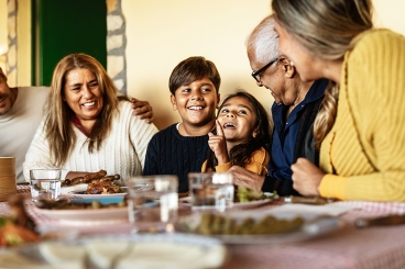 varying ages of diverse family members sitting at a dining table smiling